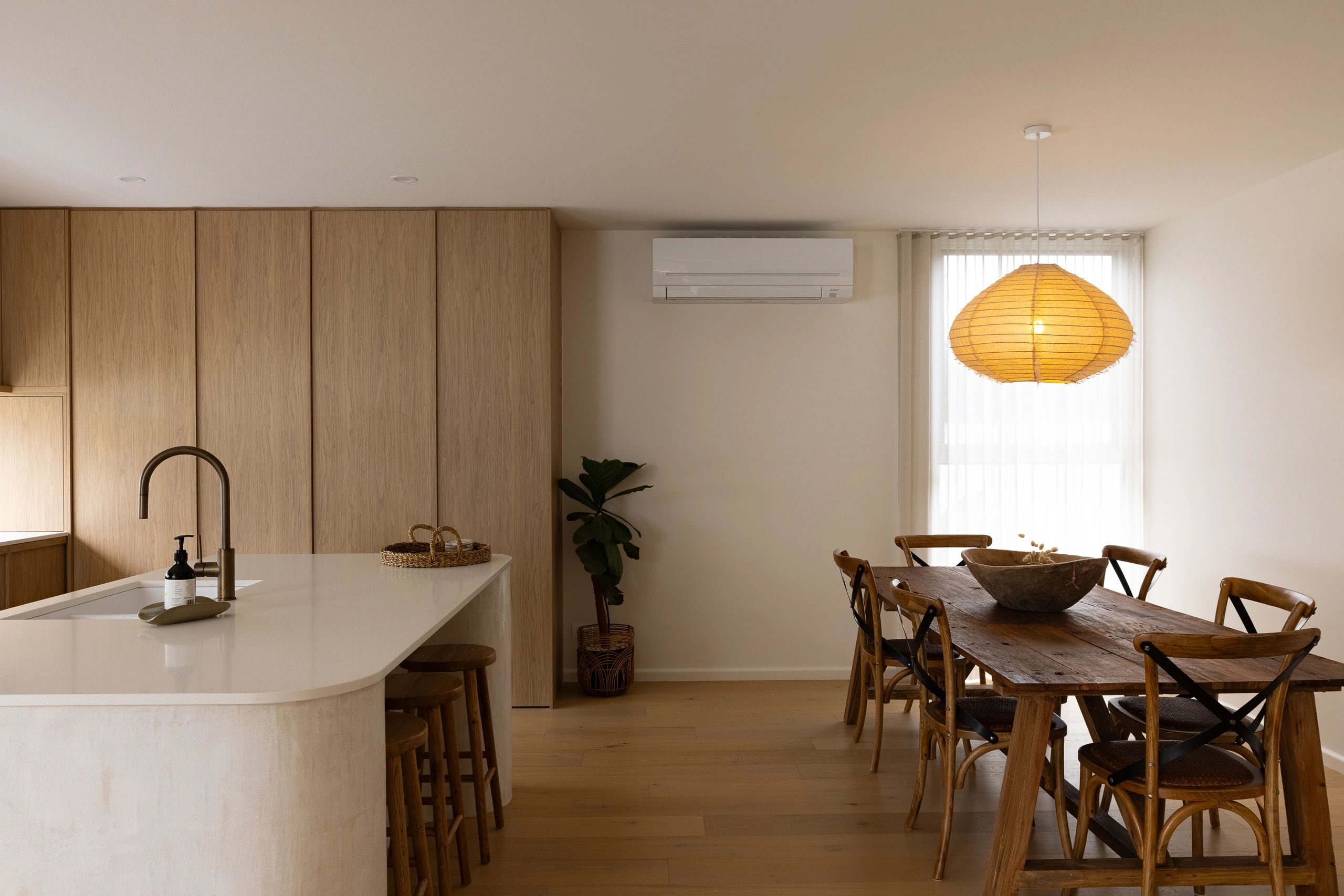 Minimalist kitchen and dining area with wooden furniture and warm lighting.