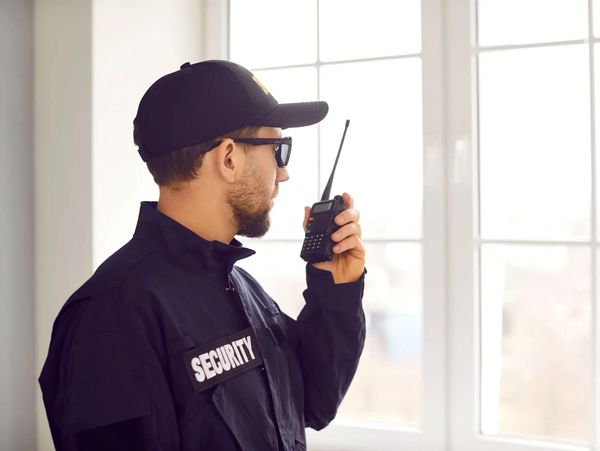 Security guard using a walkie-talkie indoors.