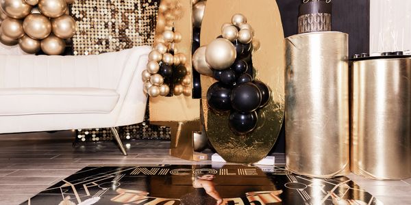 Elegant gold and black New Year's Eve party decorations with balloons and a white couch.