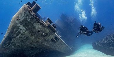 Two people scuba diving near sunken boat wreck