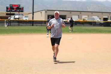 Man jogging on a baseball field during daytime.