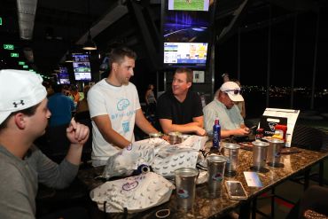 Group playing and chatting at an indoor golf simulator venue.