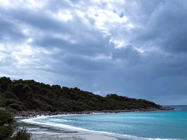 A serene beach with turquoise water under a cloudy sky.