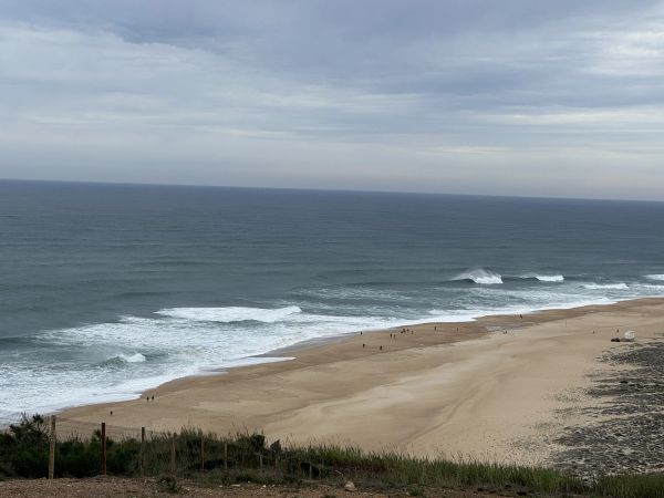 A cloudy day at a wide, sandy beach with gentle waves.