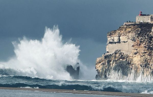 Waves crashing powerfully against a rocky cliff under a stormy sky.