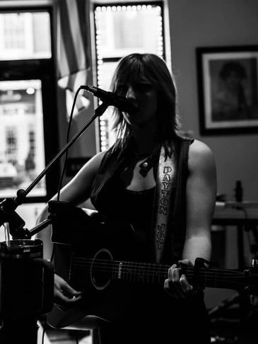 Black and white photo of a woman singing and playing guitar.