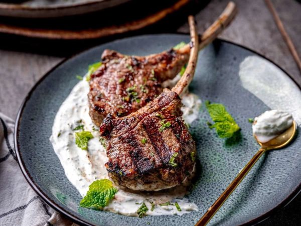 Grilled lamb chops on sauce with mint garnish.