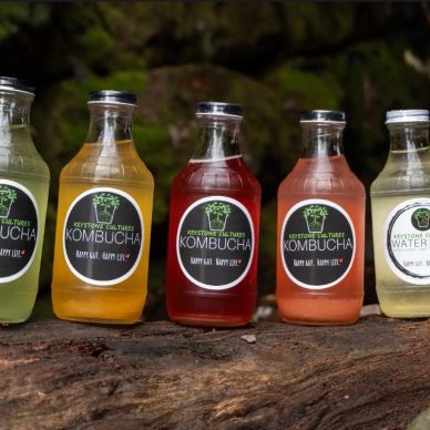 Bottles of flavored kombucha drinks on a wooden surface.