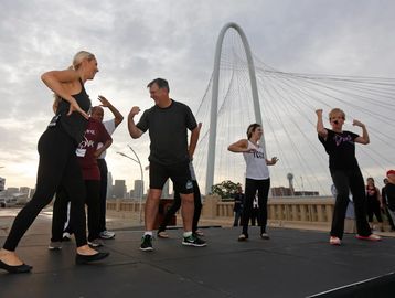Group exercising outdoors near an iconic bridge.