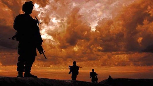 Silhouetted soldiers with rifles against an orange, cloudy sunset sky.