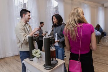 People socializing and pouring drinks at an indoor event.