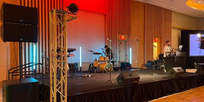 A stage set up for a musical performance with instruments and a speaker at a podium.