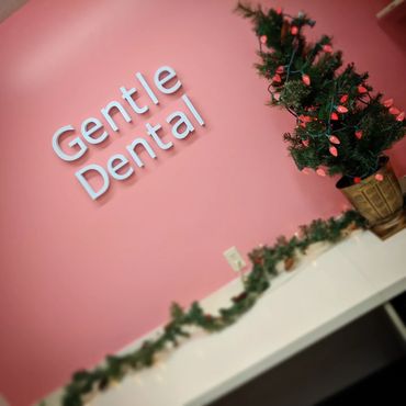 A pink wall with a white cover below it, the wall has a sign saying "Gentle Dental" and the counter 