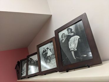 Four frames on a shelf with black and white images of various people