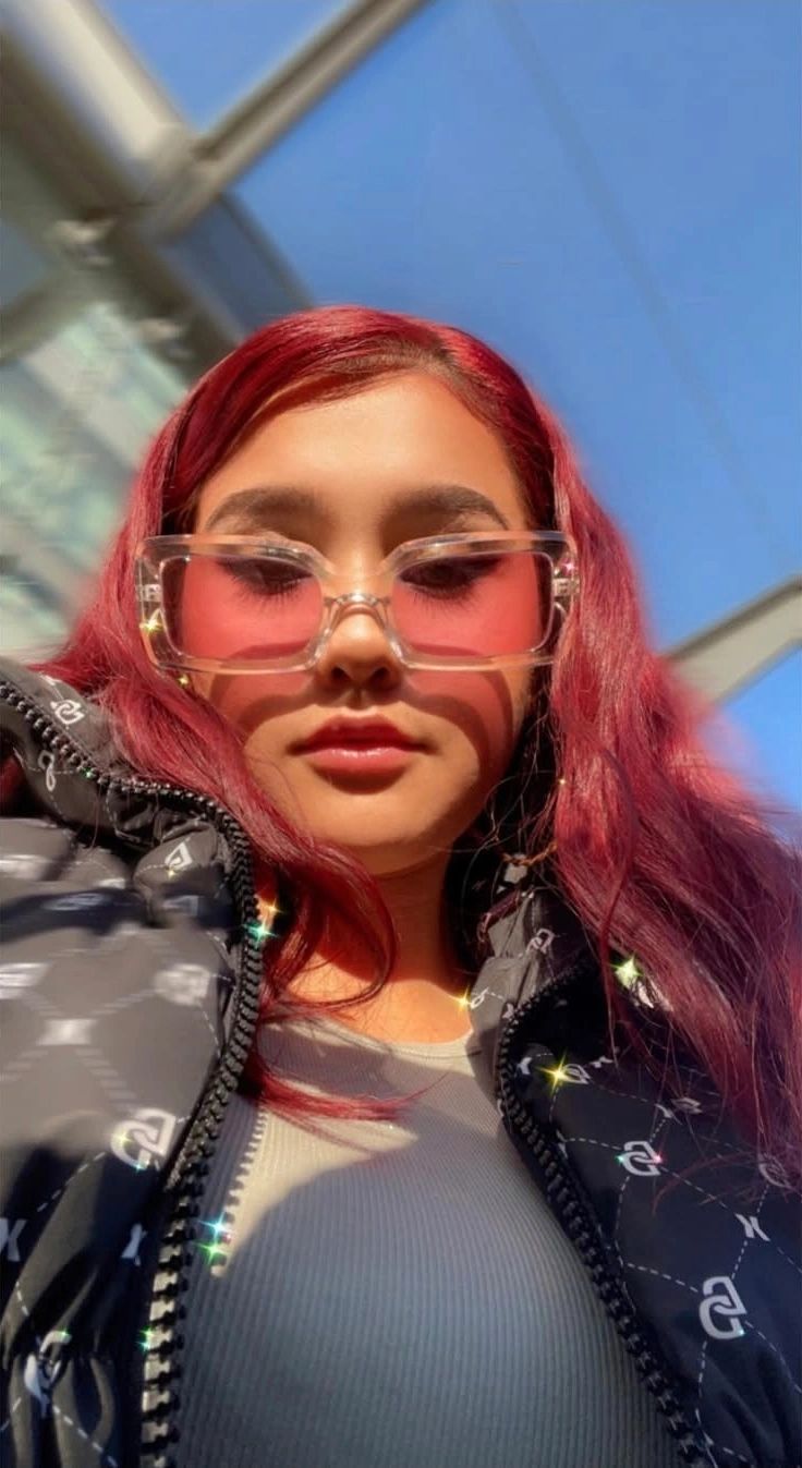 Young native woman with red hair and pink sunglasses in sunlight. Auntiez 