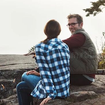 A couple sitting on rocks enjoying a scenic outdoor view.