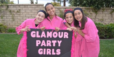 girls at spa party in pink robes hold sign