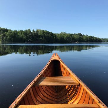 Bow of canoe overlooking calm lake and shoreline