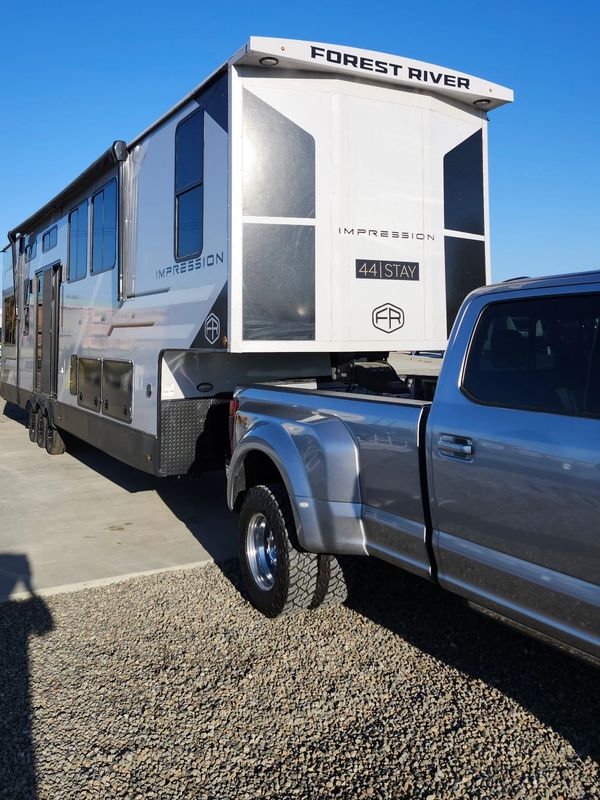 A truck towing a Forest River Impression 44|Stay trailer on a sunny day.