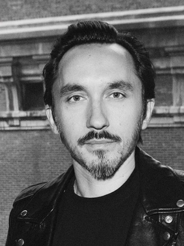 Black and white portrait of a man with a beard wearing a leather jacket.