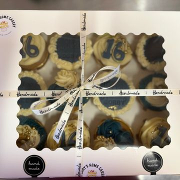Box of handmade decorated cupcakes with blue and gold accents.