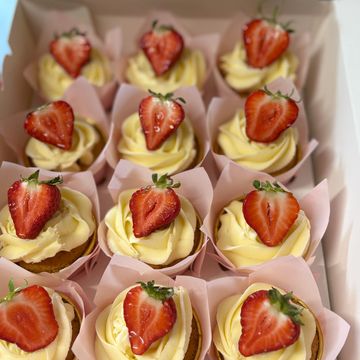 Cupcakes topped with creamy frosting and fresh strawberry halves.