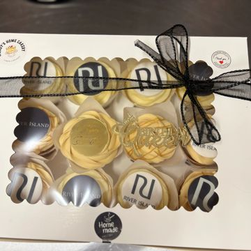 Elegant box of decorated cupcakes with a black ribbon.