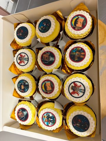 Box of twelve Roblox-themed cupcakes with vibrant yellow frosting and character toppers.