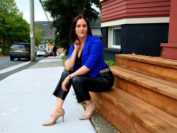 A realtor in St. John’s sitting on the steps of a downtown character home. 