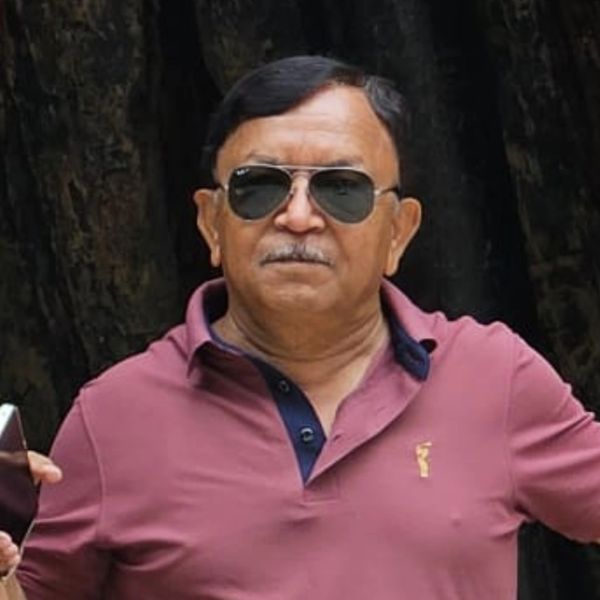 Man wearing sunglasses and maroon polo shirt posing outdoors.