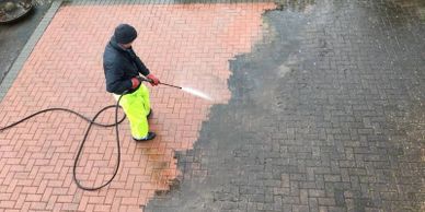 A person holding a water hose and spraying the ground