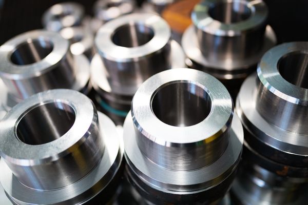 Close-up of several shiny, cylindrical metal components with hollow centers, on a blurred background