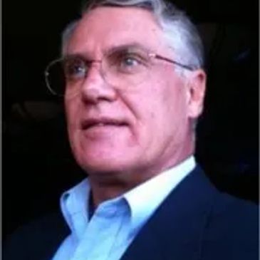 Portrait of an older man with glasses in a suit.