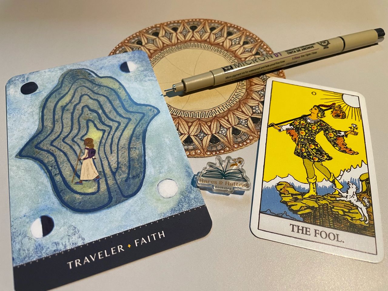 Focus card TRAVELER/FAITH from the Wild & Sacred Divine Feminine Deck, Zentangle drawing by Julie, Pen, Hares & Hatters Bookshop lapel pin, and The Fool.