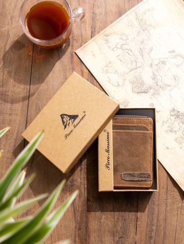 A brown leather wallet in a branded box on a wooden table with a cup of tea and a map.