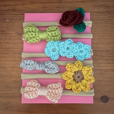 Crocheted flower and bow hair ties on pink card.