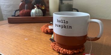A mug that says 'hello pumpkin' on a wooden table.