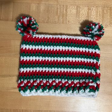 Crocheted hat with red, green, and white stripes and pom-poms.
