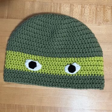 Crocheted green beanie with eye designs.