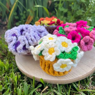 Colorful crocheted flower cupcake on a wooden plate.