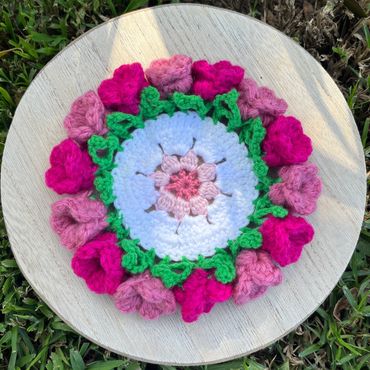Crocheted floral mandala with pink and green colors.