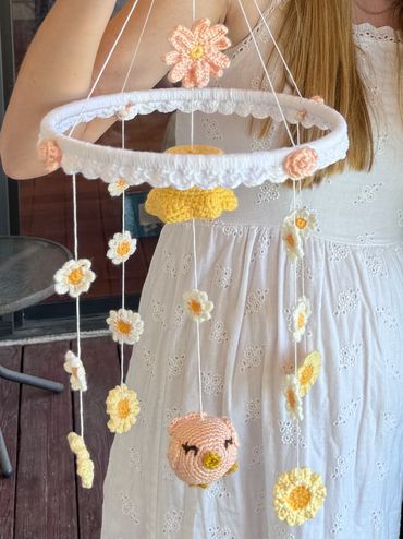Handmade floral baby mobile with crocheted flowers and a bird.