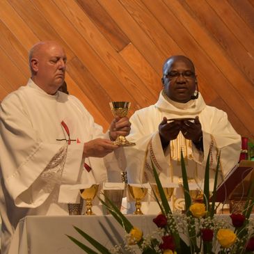 Two priests performing a religious ceremony with chalices and a host.