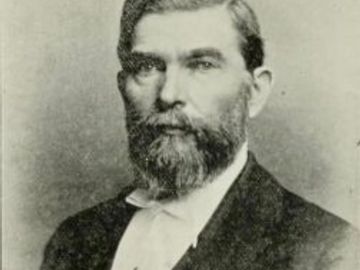 Black and white portrait of a serious bearded man in formal attire.