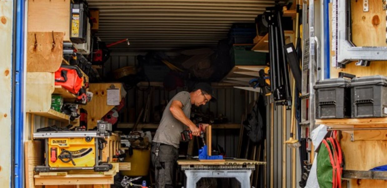 A man working with a drill inside a well-organized workshop.