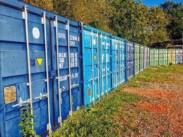 A row of colorful shipping containers lined up outdoors under a clear sky.