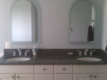 Double sink bathroom vanity with two mirrors and soap dispenser.