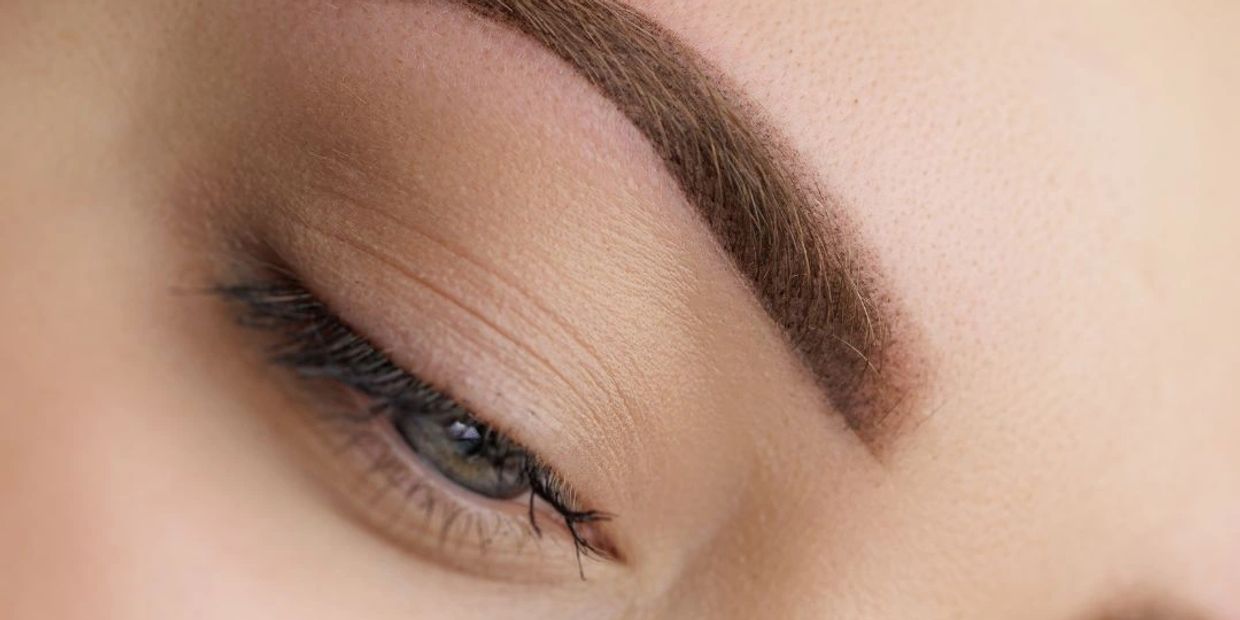 Close-up of a closed eye with well-defined eyebrow and natural skin texture.