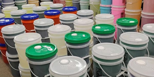 Rows of colorful plastic buckets with lids arranged closely together.