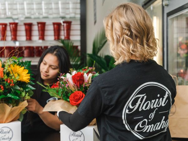 Two florists arranging colorful flower bouquets in a shop.